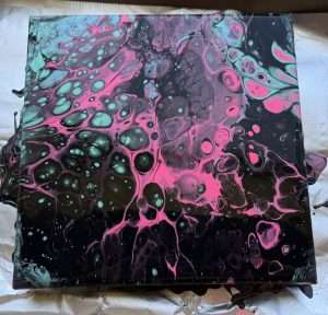 Dark and dramatic student paint pour canvas in black, hot pink, and mint with large fluid art cells created at a Paint Pour Academy class