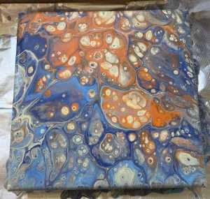 Beginner student canvas featuring intricate acrylic paint pouring cells in cobalt blue, burnt orange, and cream created at Paint Pour Academy